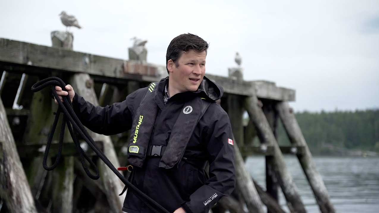 A salmon farmer working with some ropes outside.