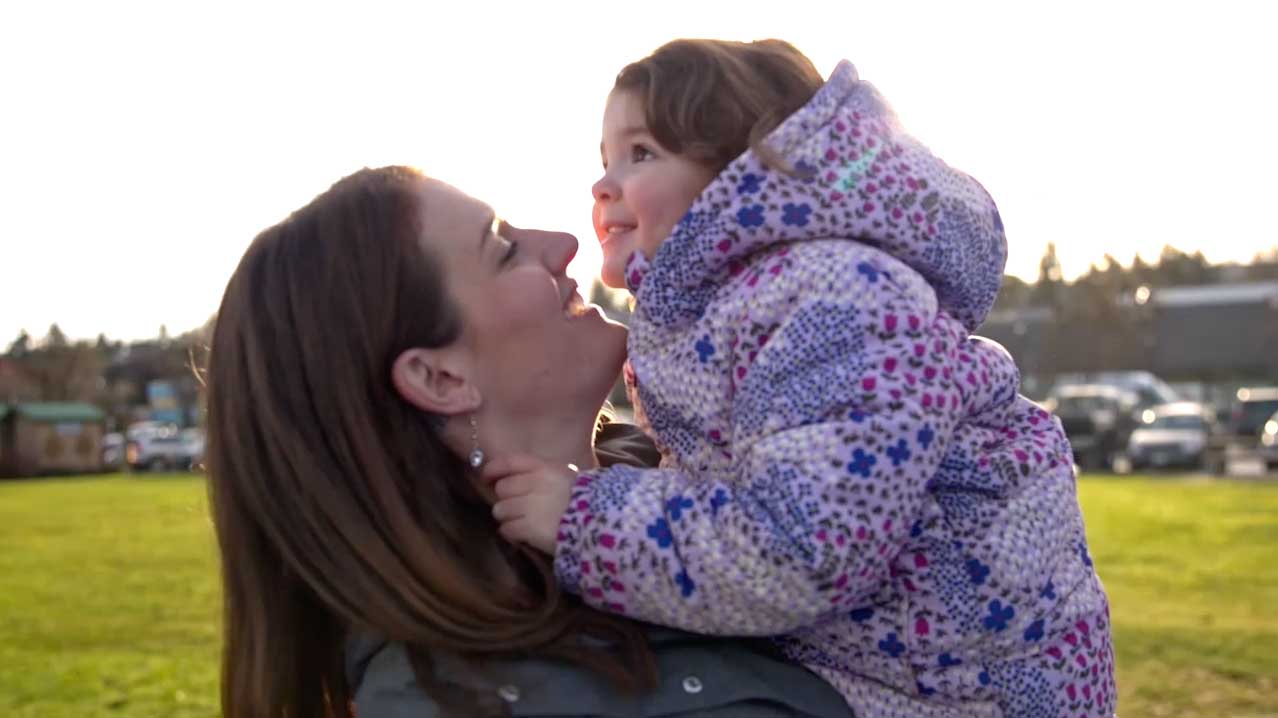 A woman holding her daughter outside.