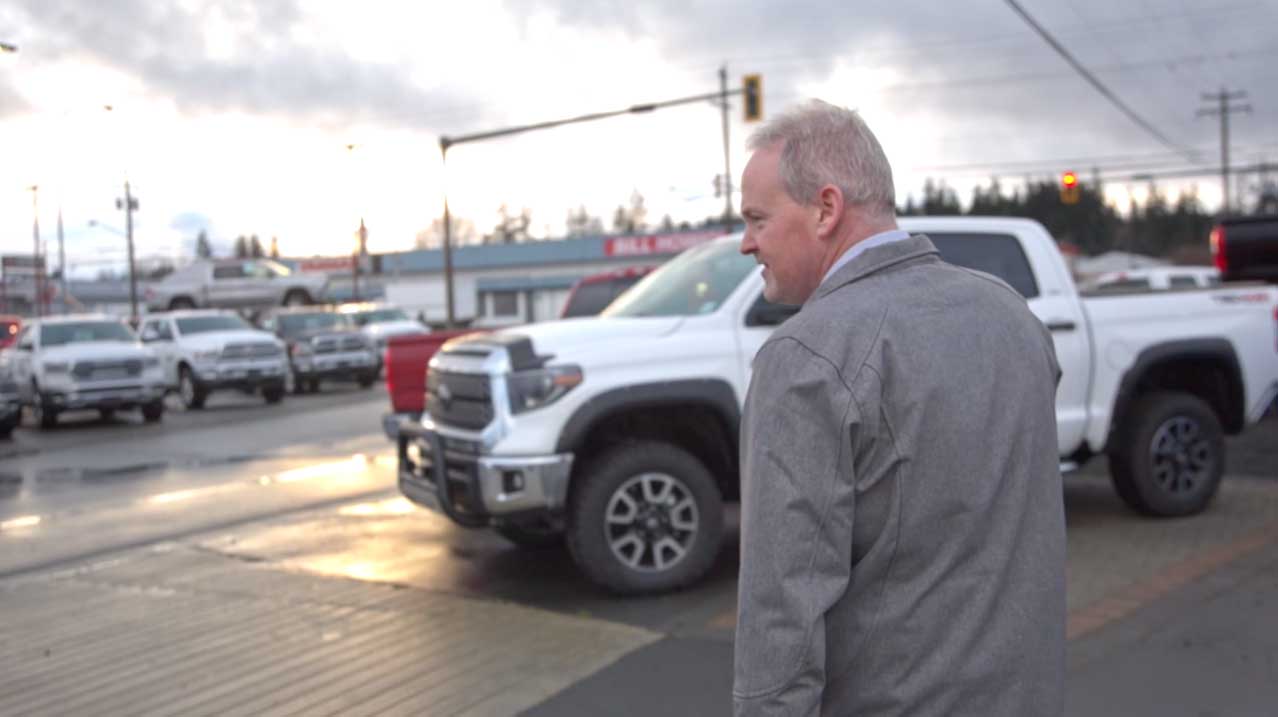 A car salesman walking outside at dealership.